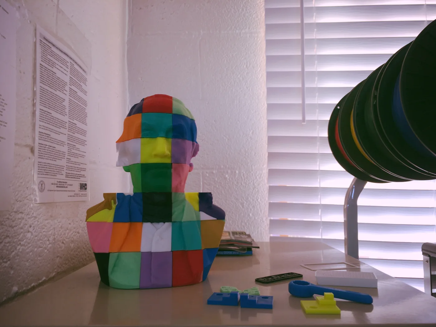 A colorful segmented 3D-printed Benjamin Franklin bust on a workbench