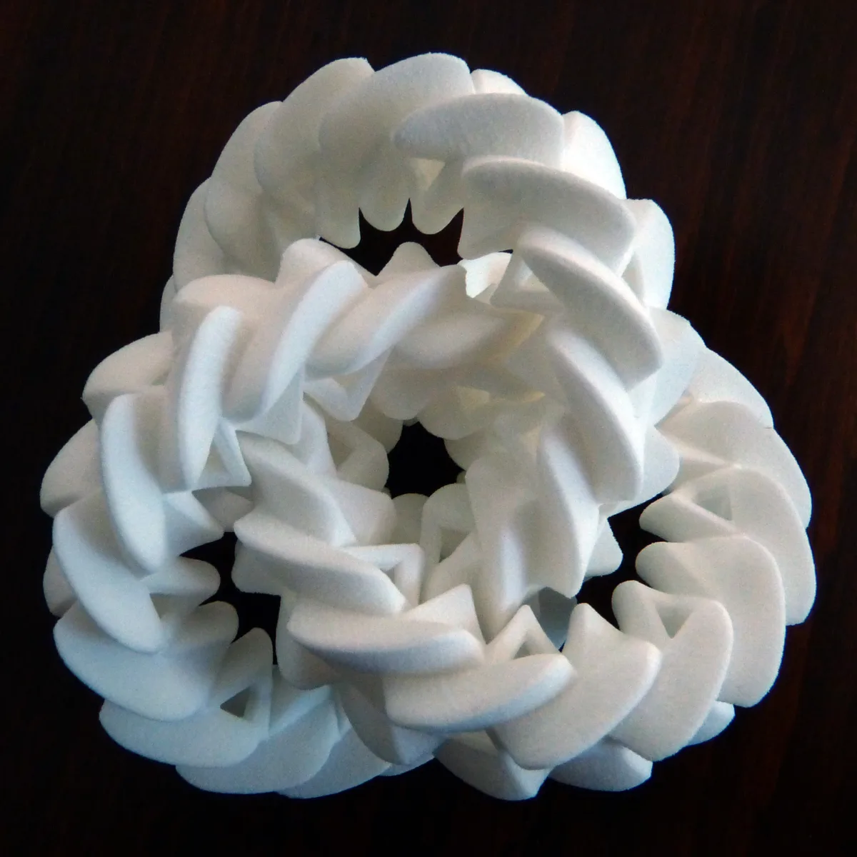 Three white interlocking 3D-printed rings with gear teeth
